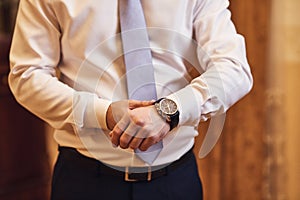 Businessman checking time on his wrist watch, man putting clock on hand,groom getting ready in the morning before wedding ceremony