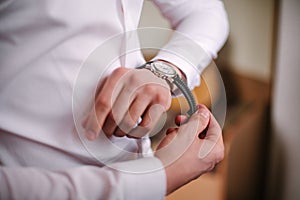 Businessman checking time on his wrist watch, man putting clock on hand,groom getting ready in the morning before wedding ceremony