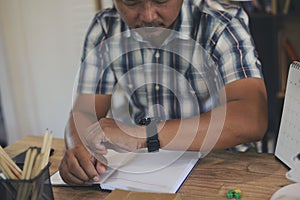 Businessman checking time and looking at smart wrist watch at home office.  Asian man seeing clock to work. Desk with laptop,