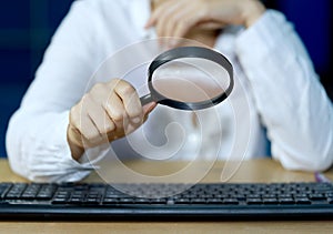 A businessman checks computer equipment with a magnifying glass Internet Information Security Concepts