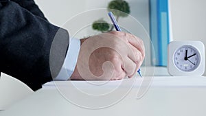 Businessman Checks the Desk Clock and Completes with a Pen a Test for an Exam