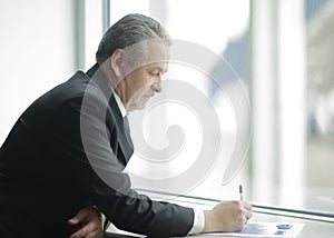 Businessman checks the financial data, standing near the office window
