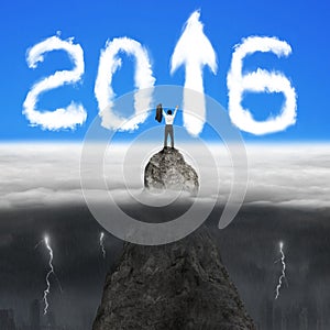 Businessman cheering on mountain peak for 2016 arrow sign clouds