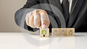 Businessman choosing light bulb icon, full of ideas and creativity on the wooden cube