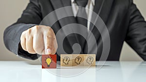 Businessman choosing light bulb icon, full of ideas and creativity on the wooden cube