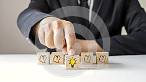 Businessman choosing light bulb icon, full of ideas and creativity on the wooden cube