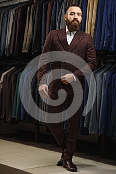 Businessman in classic vest against row of suits in shop