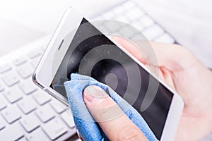 Businessman Cleaning A Smartphone Screen Of Dust, Dirt And Fingerprints With A Cleaning Wipe At His Desk