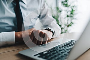 Businessman with clenched fists at office desk in front of laptop computer