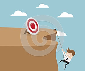 Businessman Climbing Cliff To Go To Target