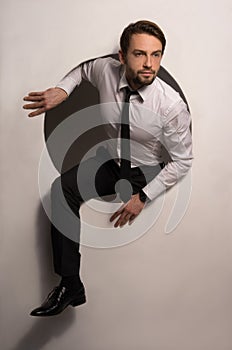 Businessman climbing out of a circular hole