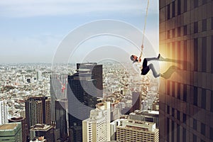 Businessman climbs a building with a rope. Concept of determination