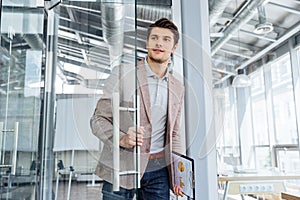 Businessman with clipboard entering the door in office
