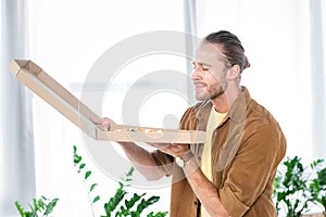 Businessman with closed eyes smelling pizza in box