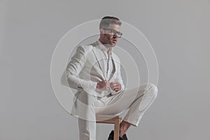 Businessman closing his jacket while sitting on a chair