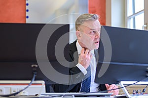 Businessman clutching at his collar with shocked look