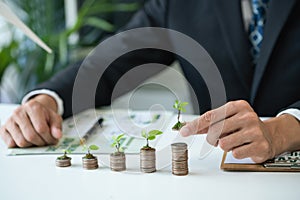 Businessman with coin stack at his office as sustainable money growth. Gyre