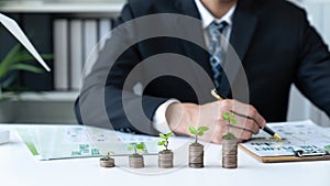 Businessman with coin stack at his office as sustainable money growth. Gyre