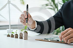 Businessman with coin stack at his office as sustainable money growth. Gyre