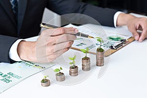 Businessman with coin stack at his office as sustainable money growth. Gyre