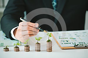 Businessman with coin stack at his office as sustainable money growth. Gyre