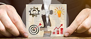 Businessman collects puzzles with the image of the attributes of doing business. Strategy planning concept. Organization of the