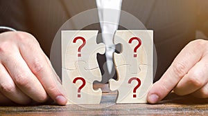 Businessman collects puzzles with question marks. Asking questions, searching for truth. Riddle mystery, investigation and