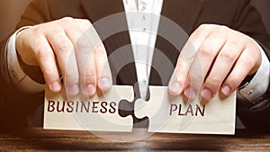 Businessman collects puzzles with the word Business Plan. Business operations program. Organization and management of processes