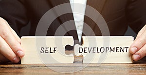 Businessman collects puzzles with the word Self-development. Concept of new business skills and motivation. Personal and career