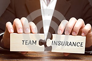 Businessman collects puzzles with the words Team Insurance. Security and safety in a business team. Care for employees. A