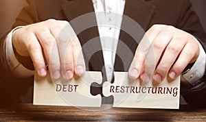 Businessman collects wooden blocks with the word Debt Restructuring. Debts relief. Changing loan repayment terms. Changing the