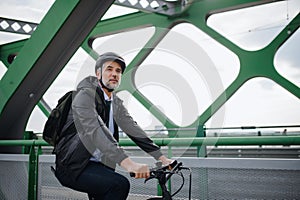 Businessman commuter on the way to work, riding bike over bridge, sustainable lifestyle concept.