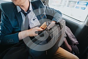 Businessman commuting in car with briefcase, focused on work tasks