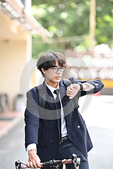 Businessman commuting to work with a bicycle and checking time on wrist watch.
