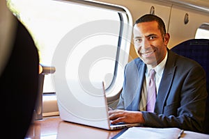 Businessman Commuting To Work On Train And Using Laptop