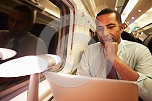 Businessman Commuting To Work On Train And Using Laptop