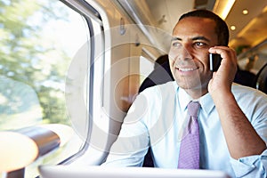 Businessman Commuting To Work On Train Using Mobile Phone