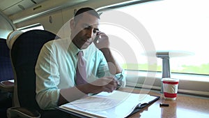 Businessman Commuting To Work On Train Using Mobile Phone