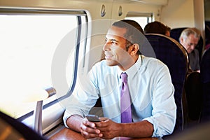 Businessman Commuting To Work On Train Using Mobile Phone photo