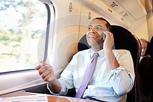 Businessman Commuting To Work On Train Using Mobile Phone photo