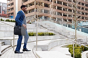 Businessman Commuting To Work Walking Down Steps To Railway Station