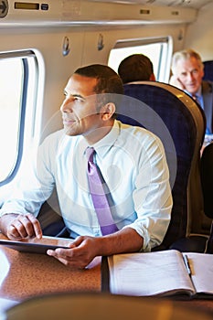Businessman Commuting On Train Using Digital Table