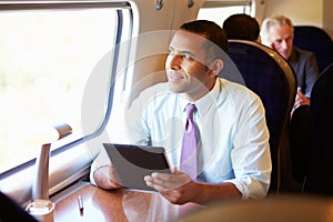 Businessman Commuting On Train Using Digital Tablet