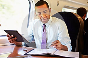 Businessman Commuting On Train Using Digital Tablet