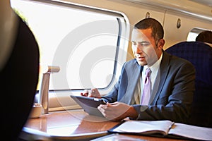 Businessman Commuting On Train Using Digital Tablet photo