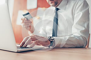 Businessman completing e-banking transaction using laptop computer and credit card