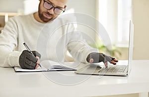 Businessman in compressive gloves work on computer write notes