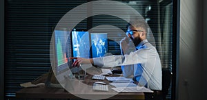 Businessman with computer sitting at desk, working late. Financial crisis concept.