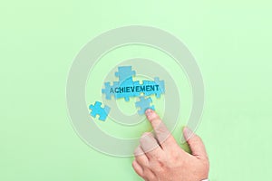 Businessman connecting puzzle pieces with the word Achievement