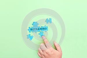 Businessman connecting puzzle pieces with the word Retraining